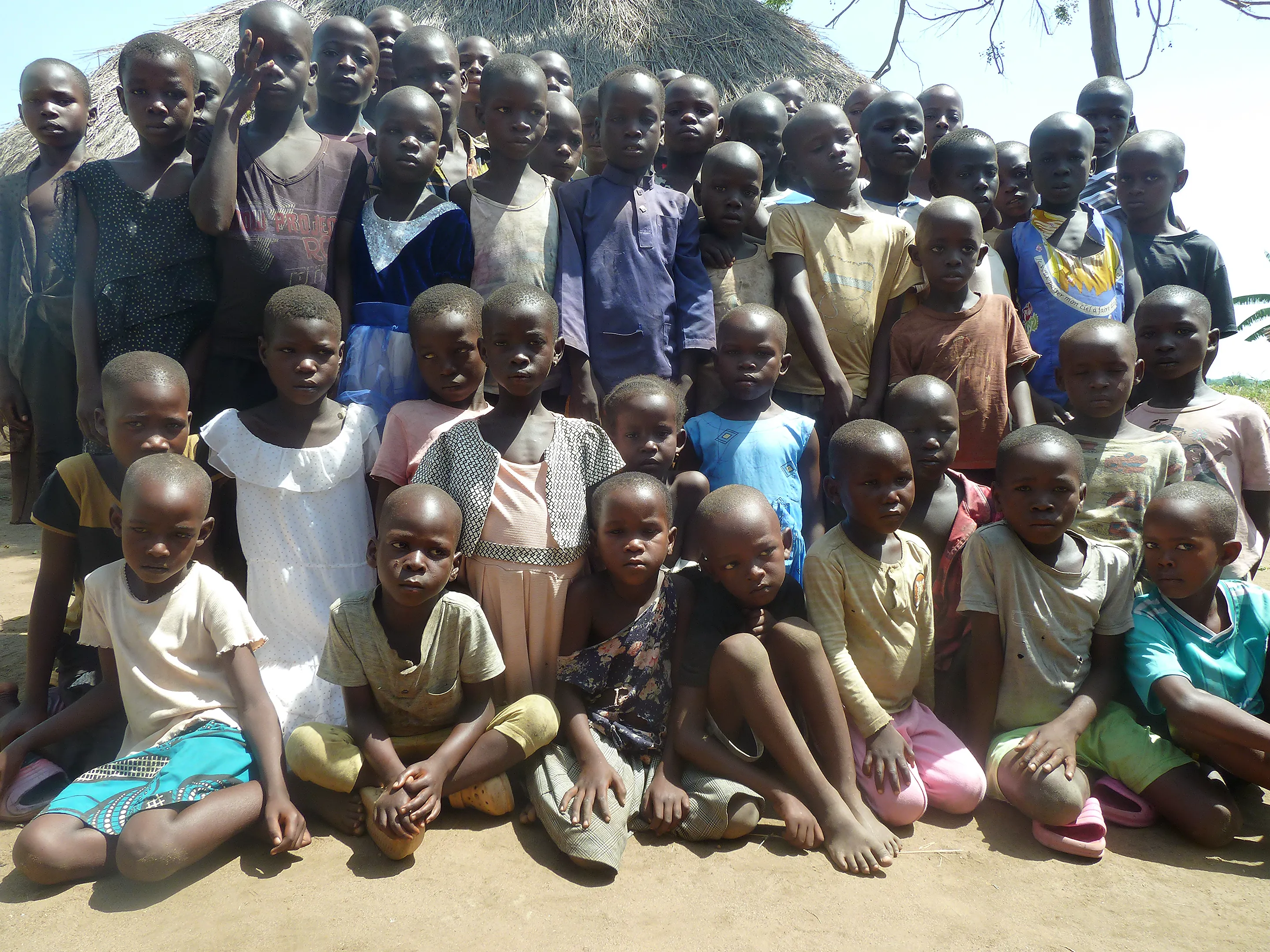 Pupils of Biggi Junior School gathered together outside a thatched hut