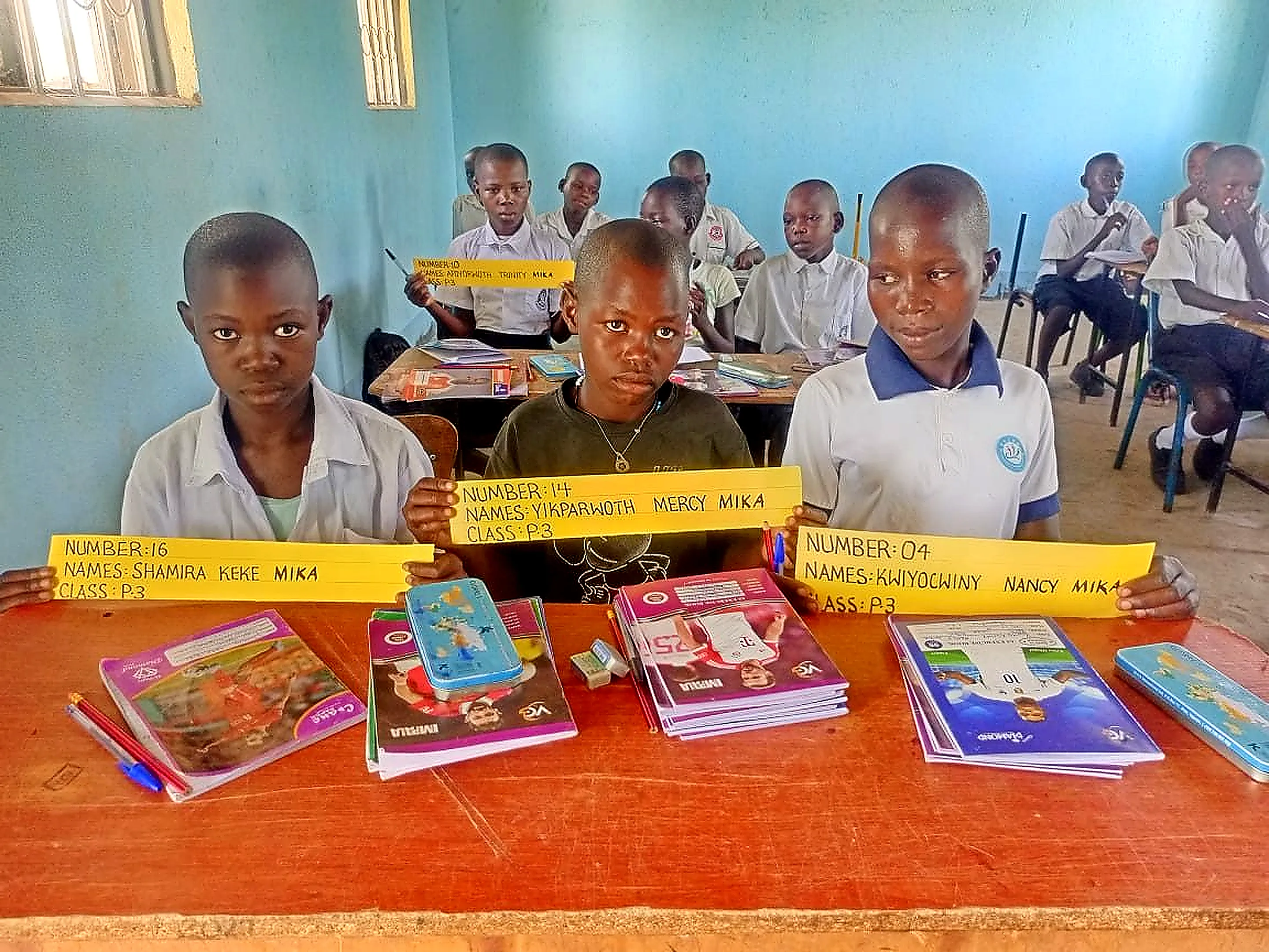 Primary 3 pupils holding up name cards at their desks in class