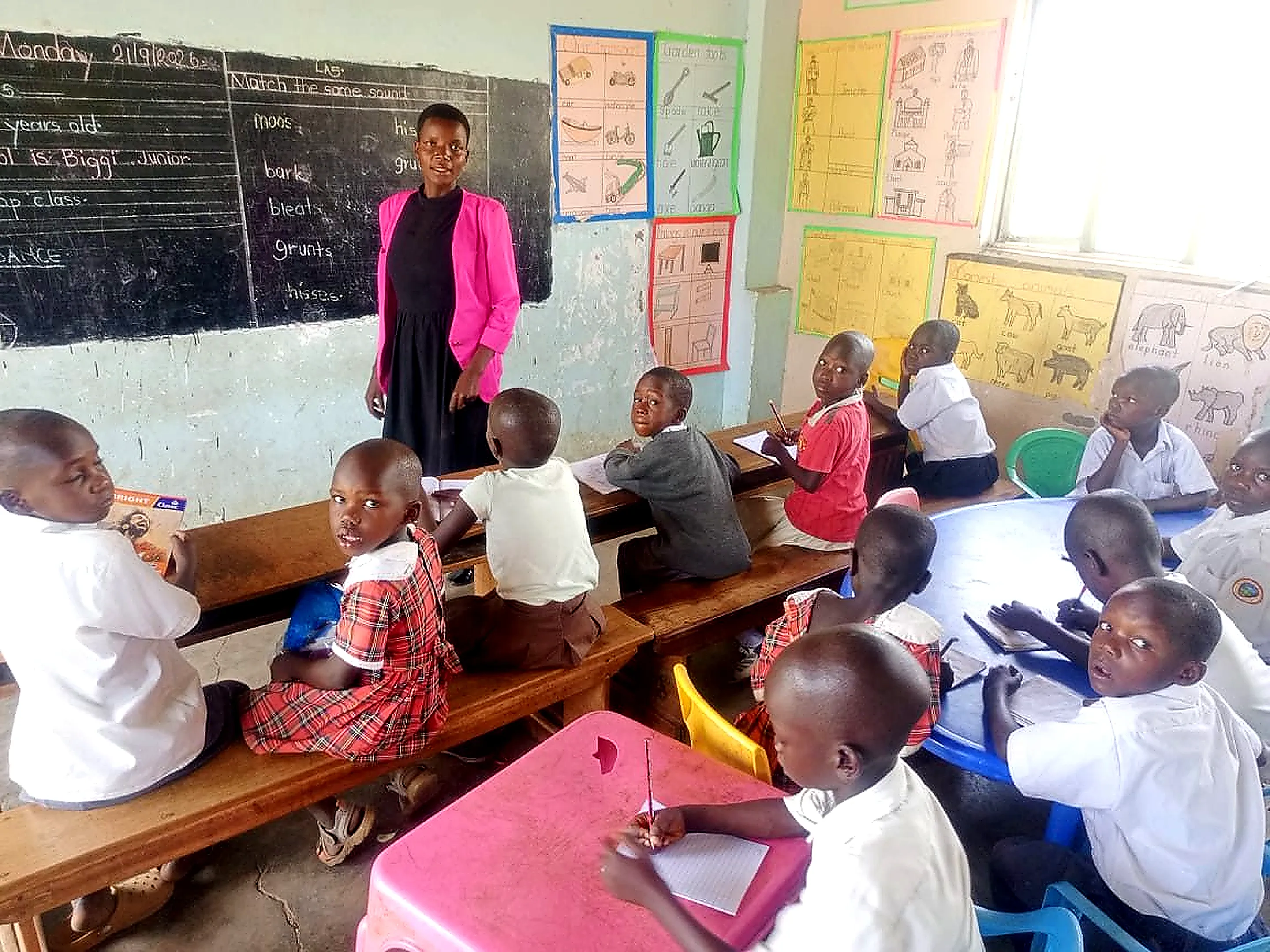 A teacher standing at the blackboard with pupils seated at their desks