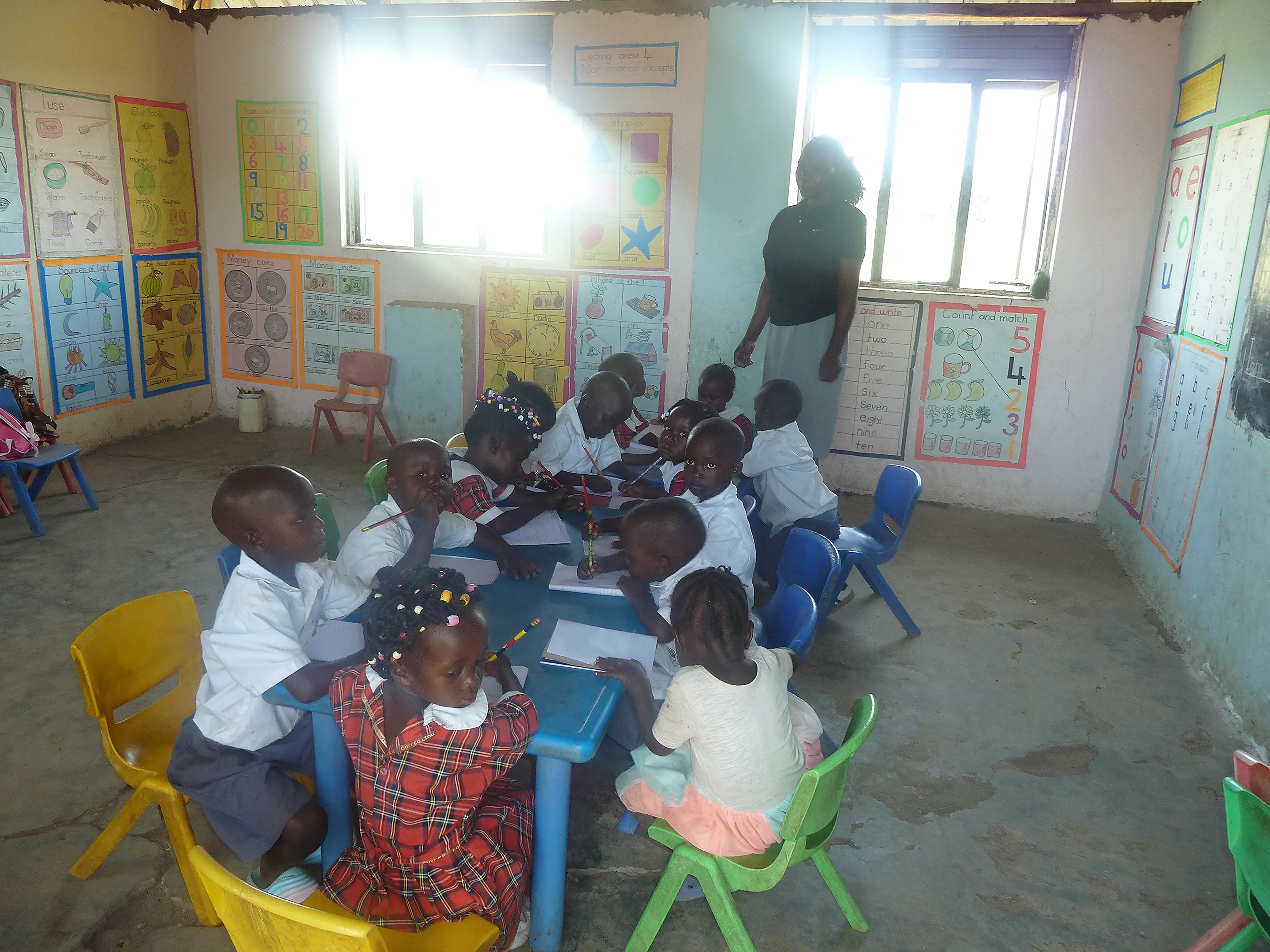 A baby class pupil writing at their desk