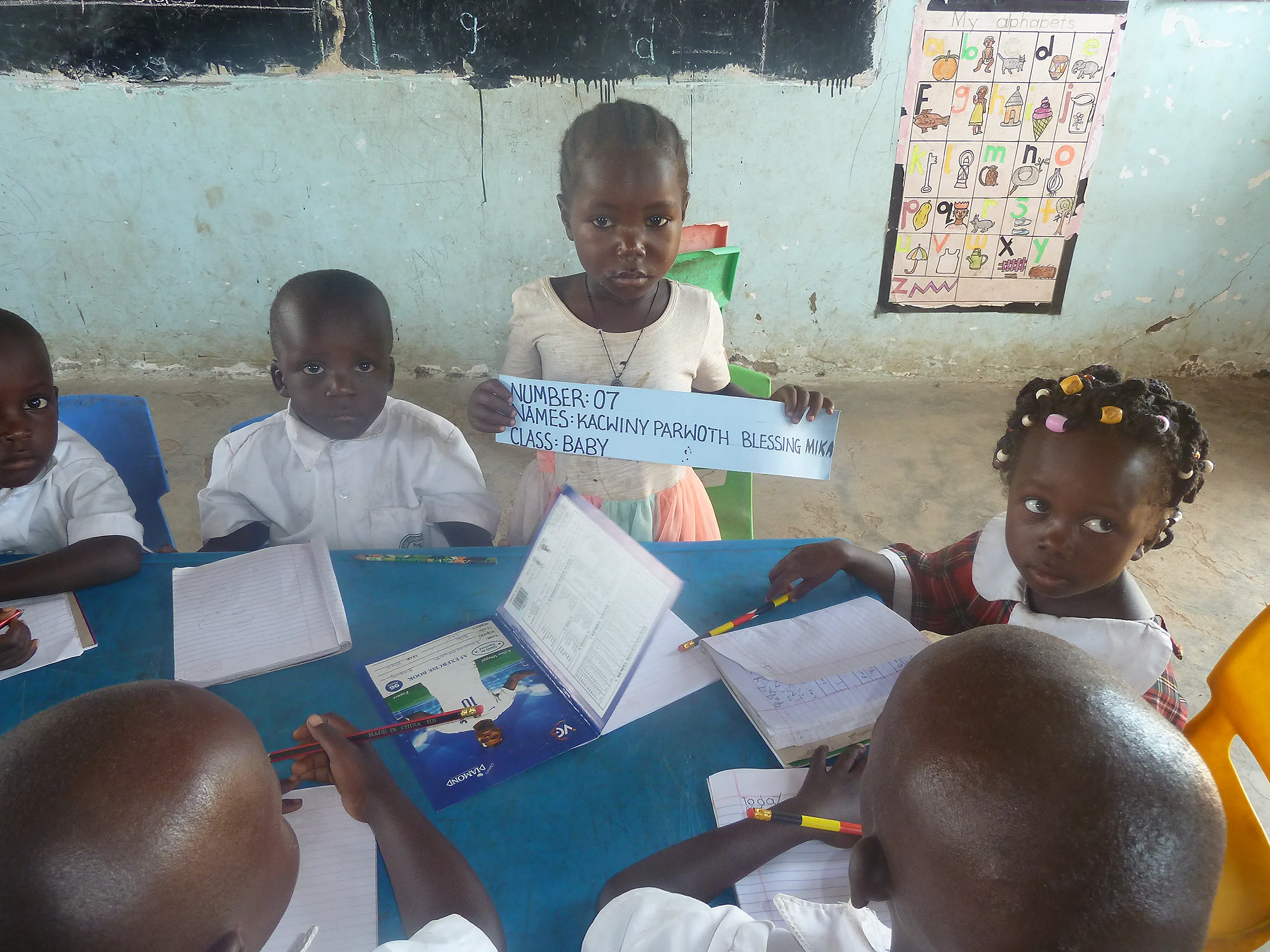 A baby class pupil writing at their desk